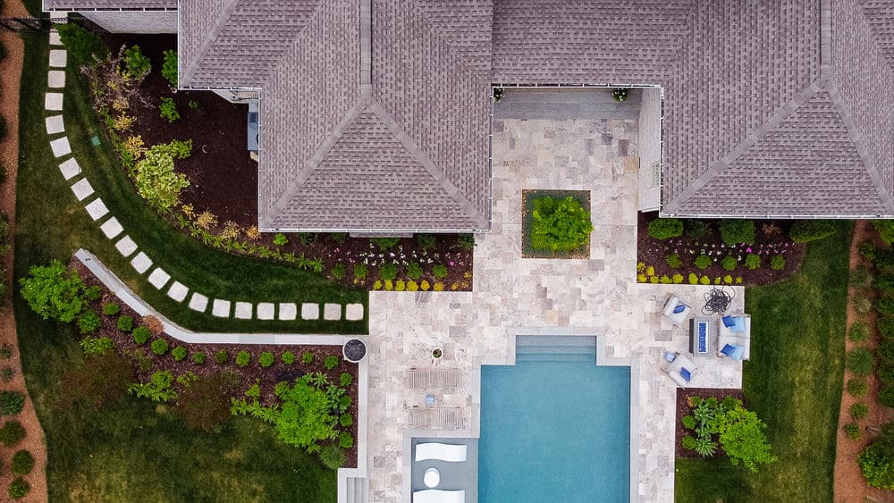 Aerial view of a modern home with a pool, landscaped garden, and stone pathways.