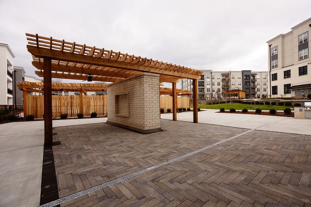 Modern outdoor living space with pergola and paved area at an apartment complex.