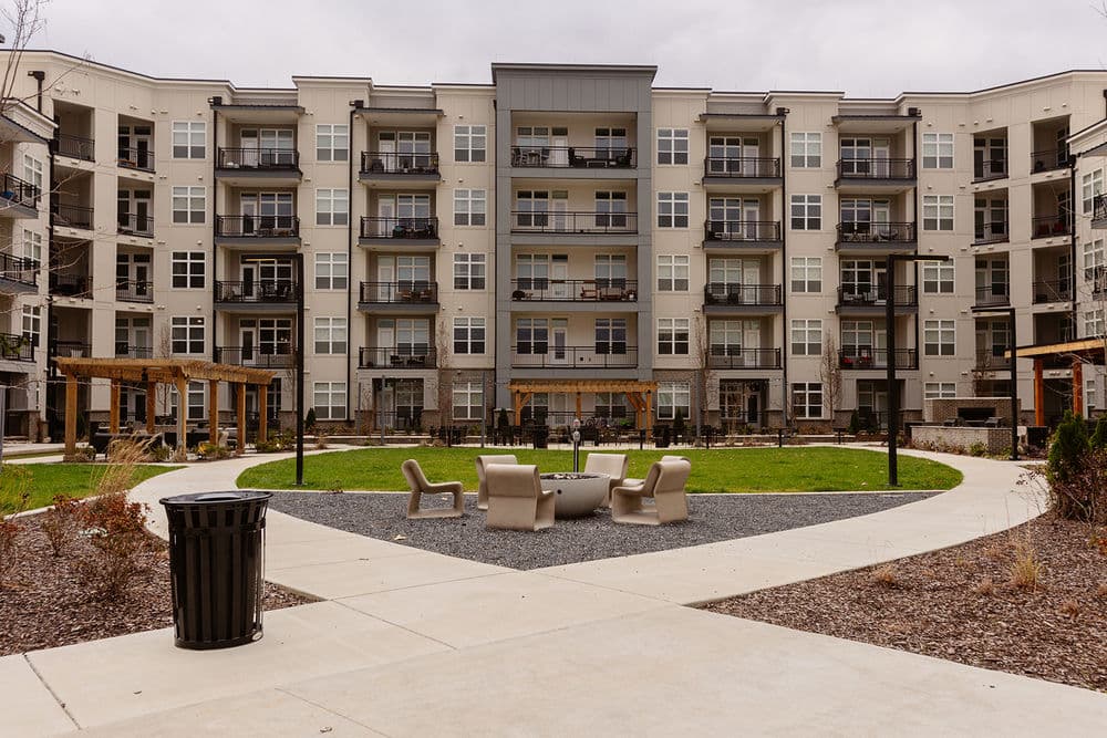 Modern apartment complex with balconies, landscaped courtyard, and gathering area.