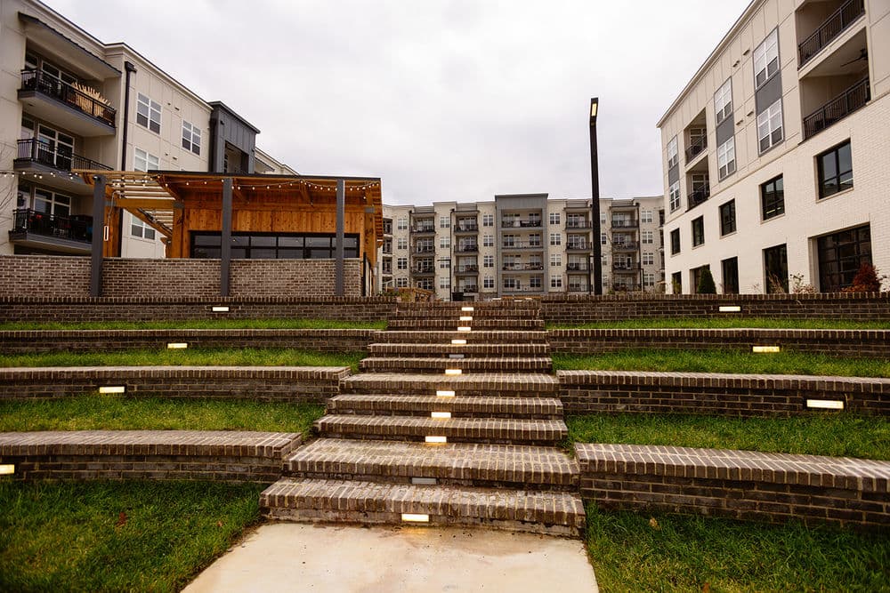 Modern apartment complex with outdoor steps and landscaped area, perfect for gatherings.