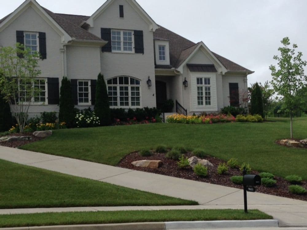 Modern suburban home with landscaped yard, colorful flowers, and a pathway.