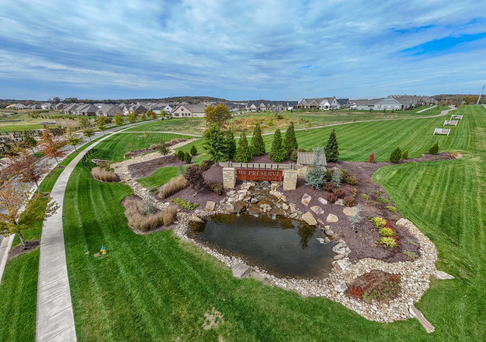 Aerial view of The Preserve community featuring green lawns, a pond, and landscaped pathways.