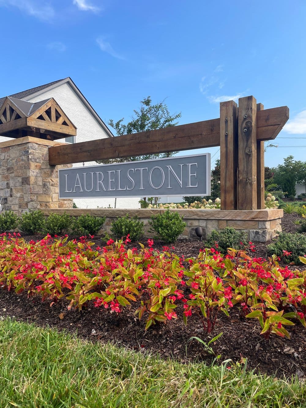 Laurelstone community sign with landscaped flowers and blue sky background.