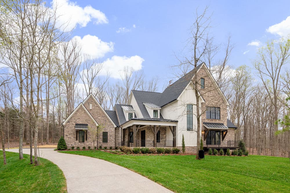 Newly built brick home with modern architecture, surrounded by trees and manicured lawn.
