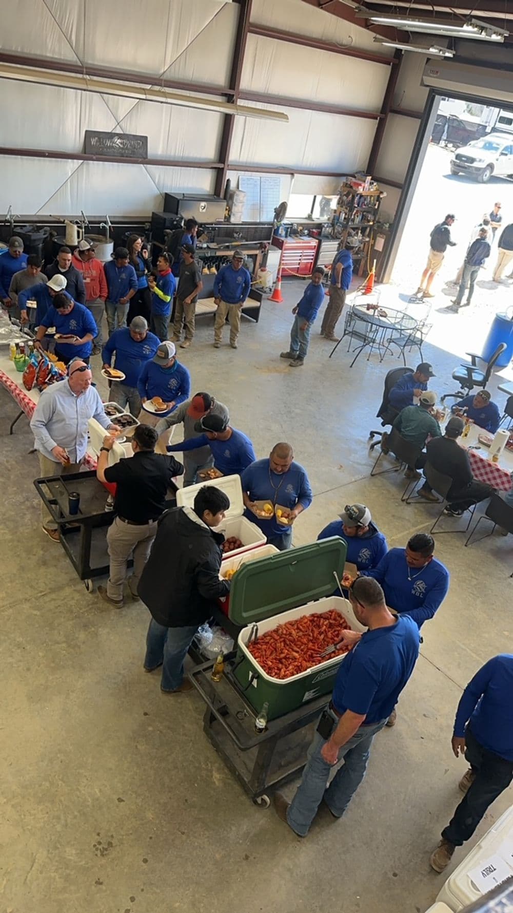 Crawfish boil event with people enjoying food and socializing in a spacious venue.