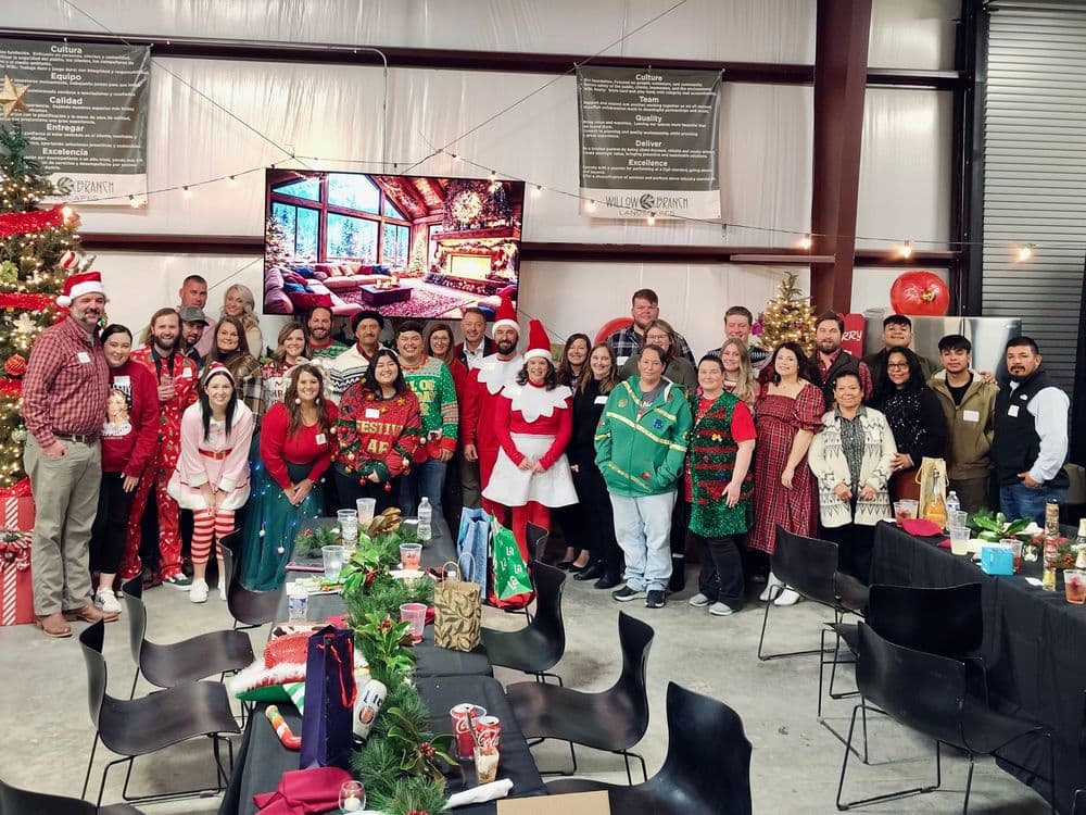 Holiday office party with festive attire, decorations, and a large group of cheerful employees.
